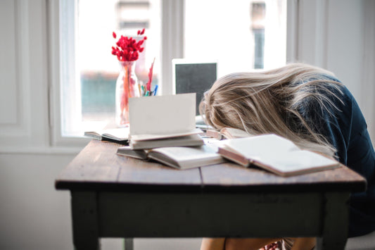 Erschöpfte Frau am Arbeitsplatz, Kopf liegt auf dem Tisch